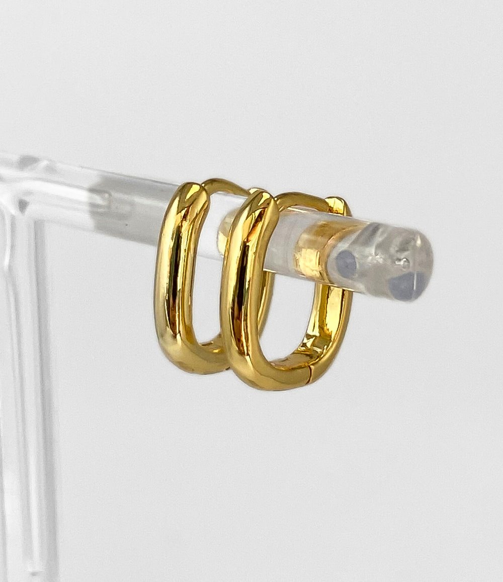 Gold hoop earrings on a clear stand against a light gray background