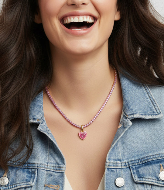 Woman wearing a pink beaded necklace with a heart pendant, smiling.