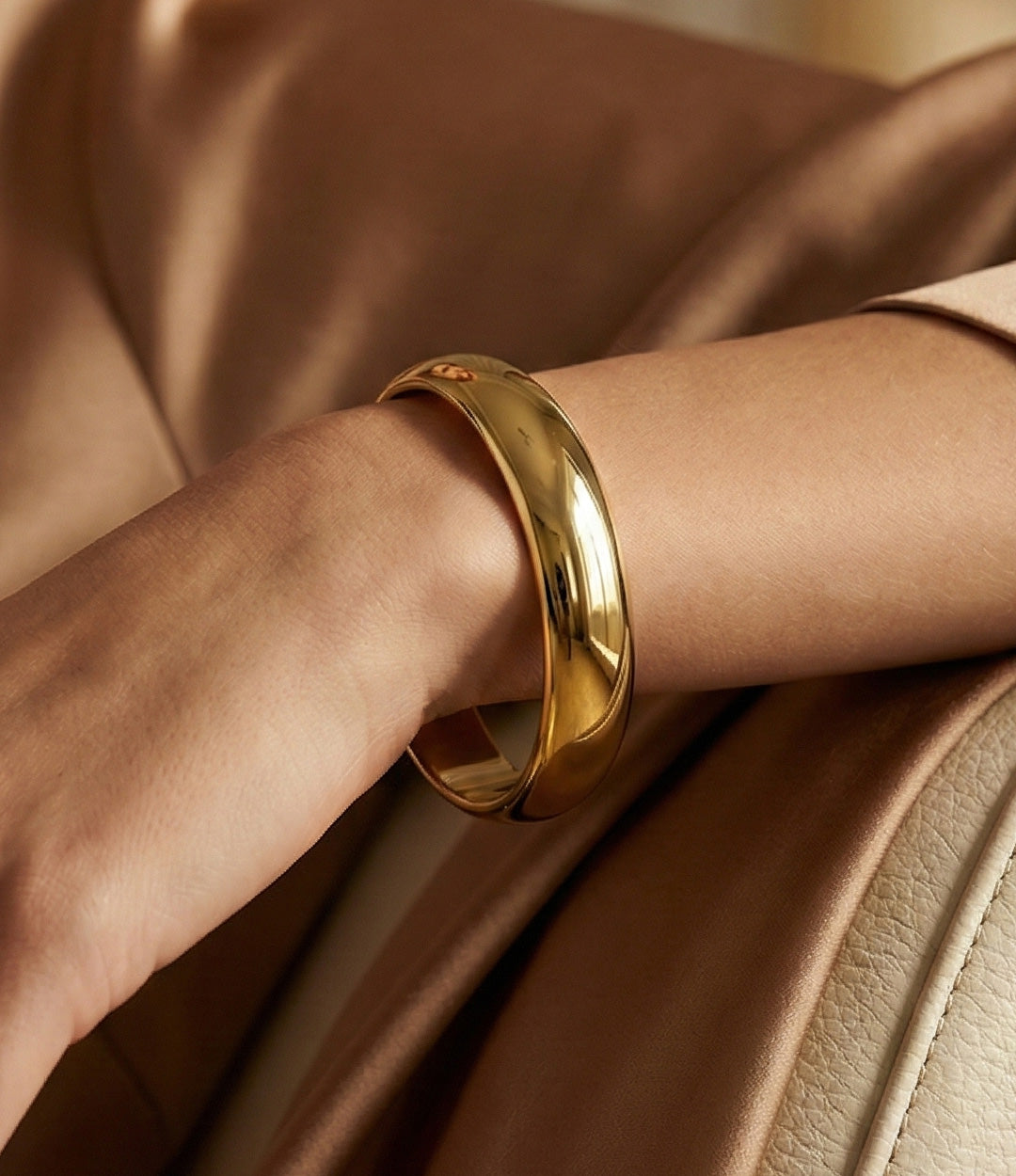 Gold bracelet on a wrist with a soft brown background