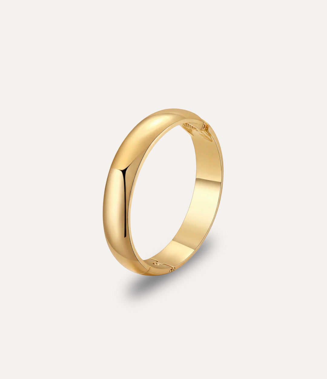 Essential Bangle in gold displayed on a neutral background with a sleek, minimalist bold design.