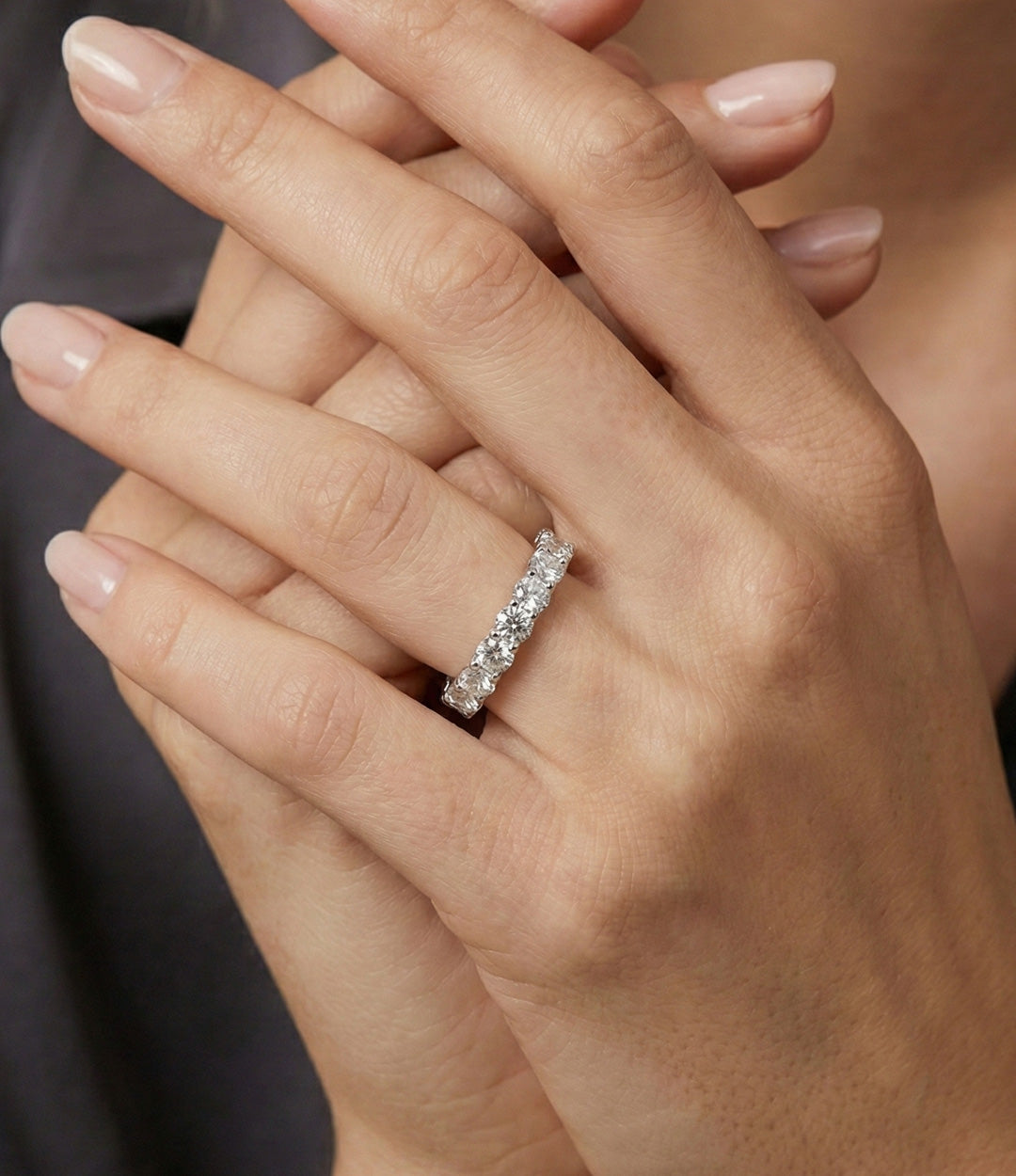 Woman's hand modeling the Eternity Band alone on the ring finger, showcasing the delicate profile and continuous line of sparkling diamonds.