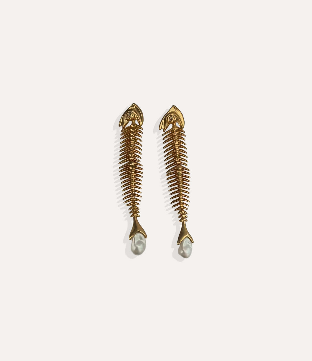 Close up of Fishbone Dangly Earrings in gold highlighting the fish skeleton motif and polished finish.