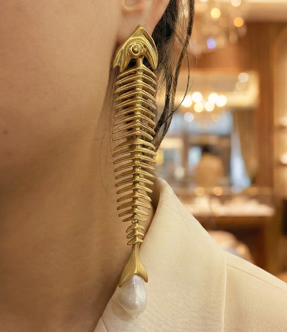 Close-up of a woman wearing a gold earring with a pearl drop.