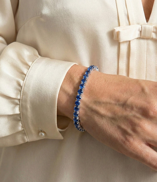 Person wearing a blue beaded bracelet on a beige background