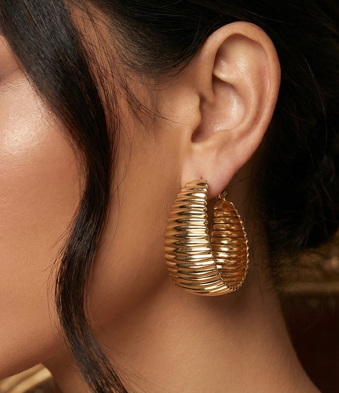 Close up of a model wearing the Haley Hoops showing the bold chunky shape and high shine finish against a neutral background.