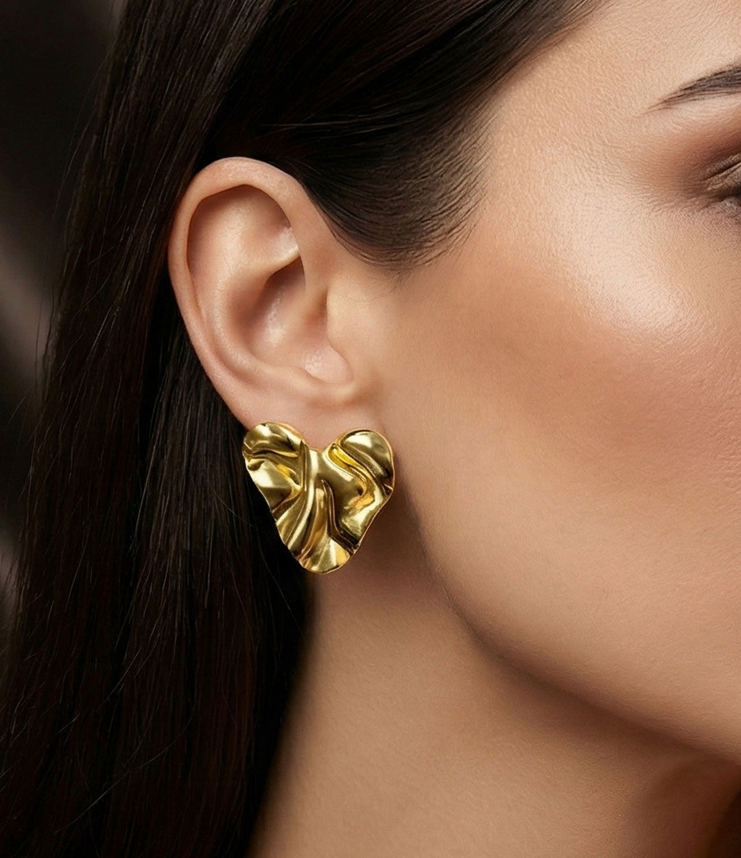 Gold earrings worn by a model with dark hair and neutral makeup.
