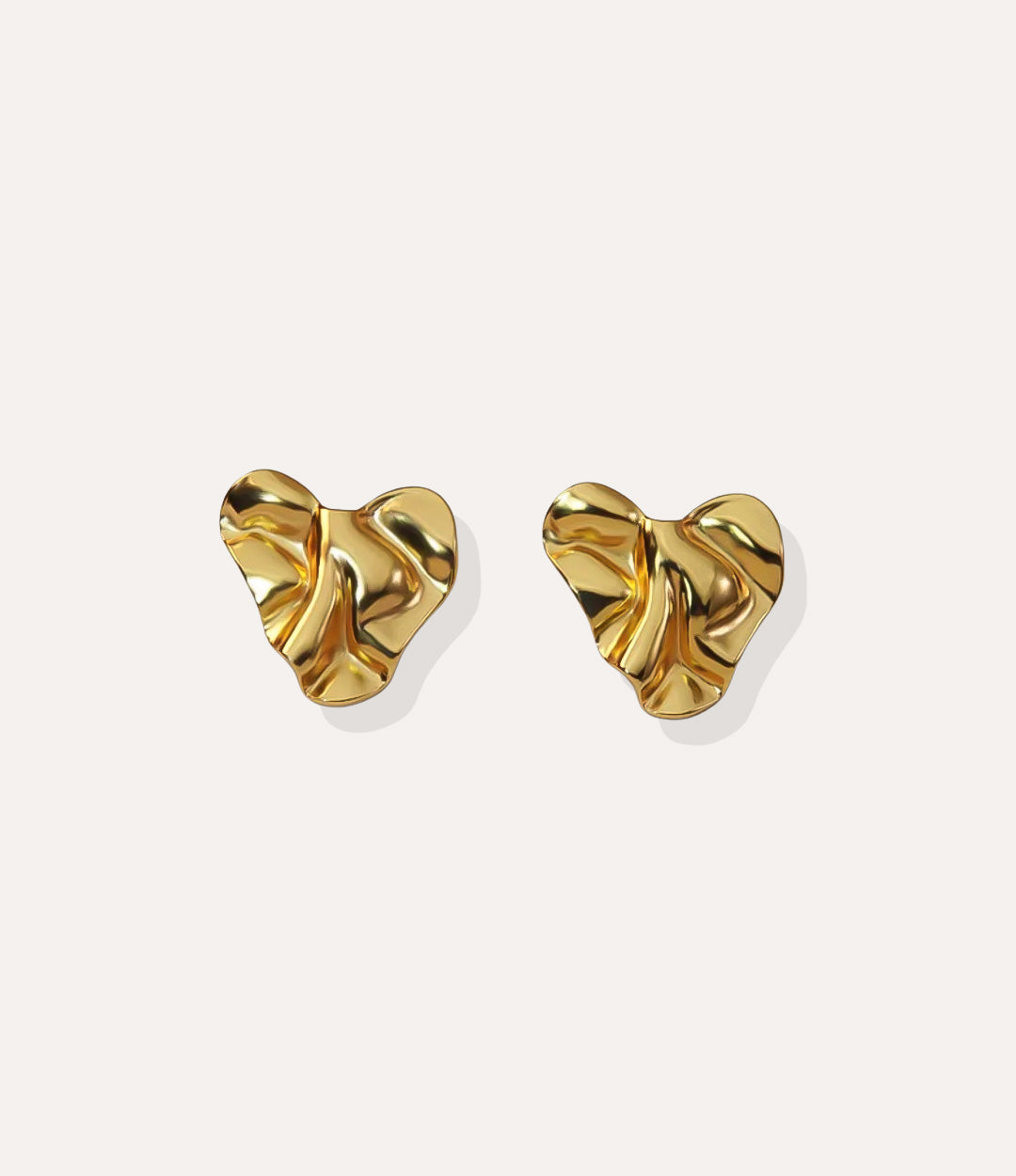 Close up of the Hammered Heart Stud earrings in gold highlighting the textured hammered finish and heart shape.