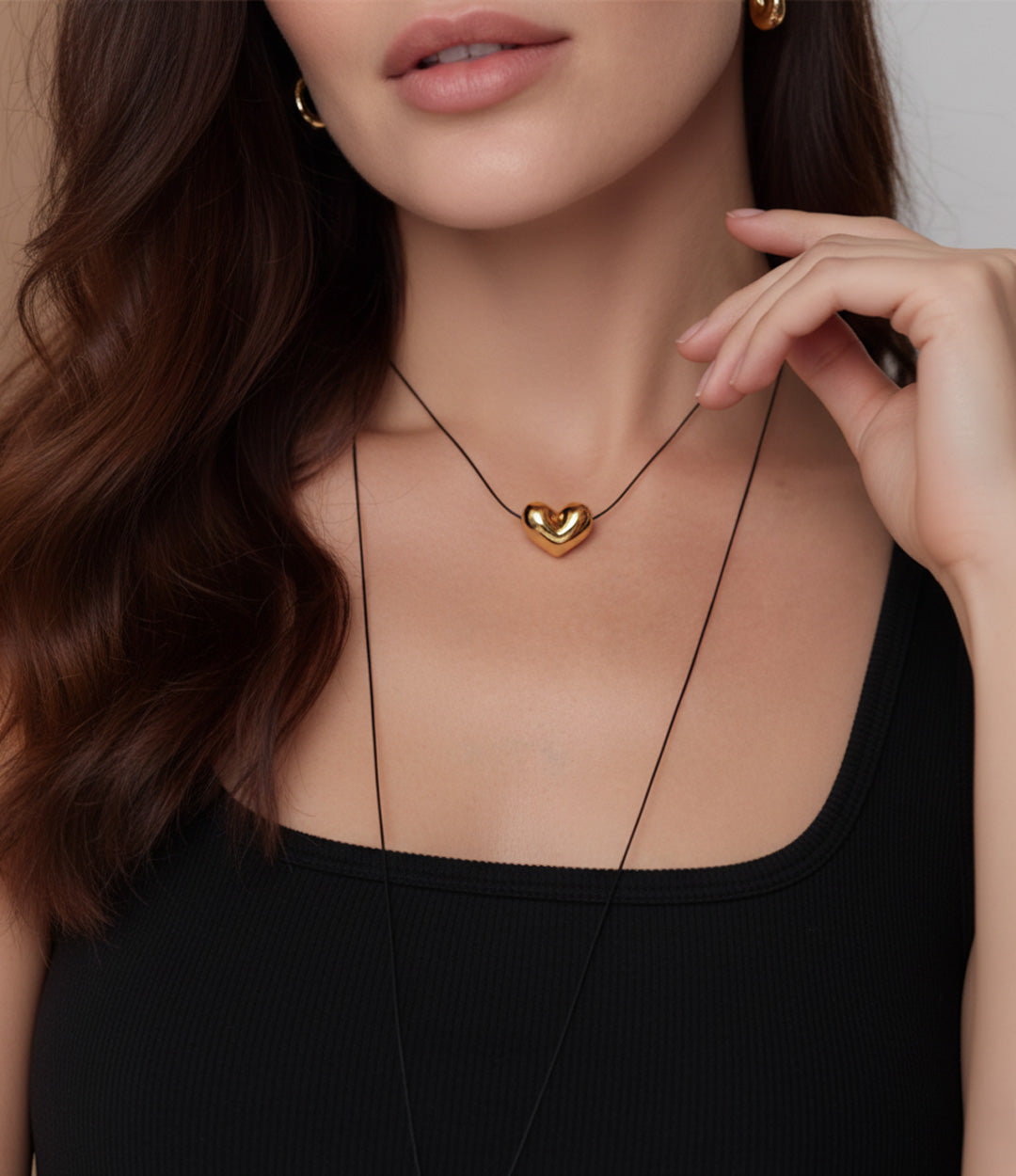 Woman wearing a gold heart-shaped necklace with a blurred background