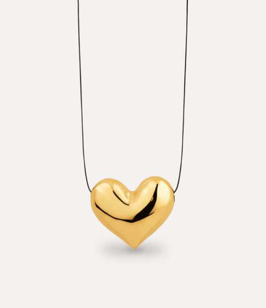 Gold heart-shaped pendant on a thin chain against a light gray background