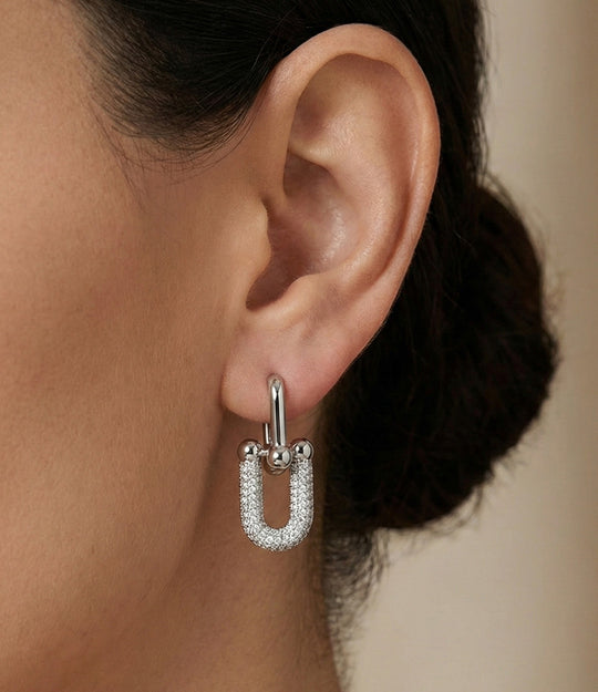 Model wearing Horse Bit Stud earrings featuring two linked horseshoe shapes in a modern minimalist design.