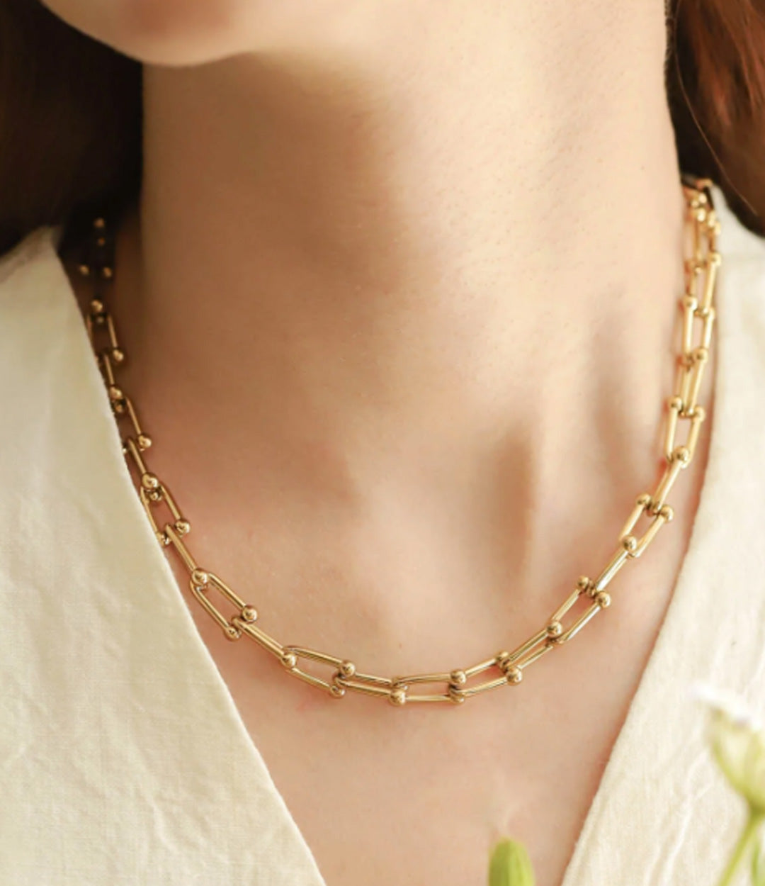 Close-up of gold textured link necklace showing rounded bead accents and polished finish on a woman.