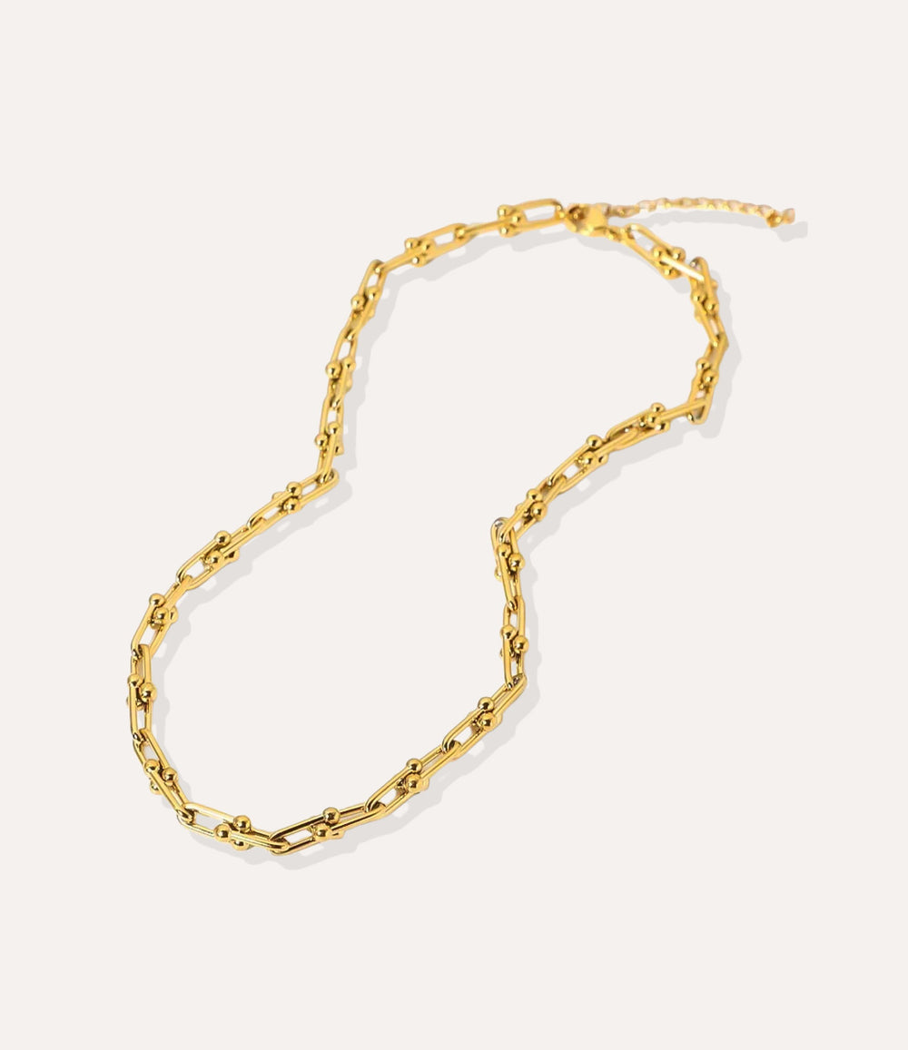 Gold beaded-link chain necklace featuring U-shaped interconnected links on a cream background.