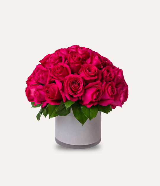 Bouquet of bright pink roses in a white container on a light gray background