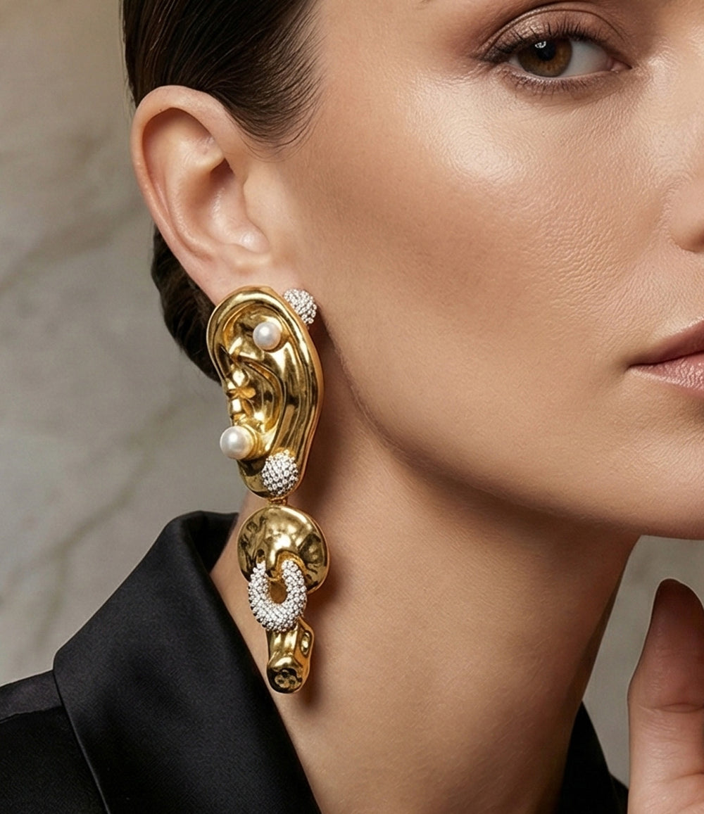 Close-up of a woman wearing gold earrings with pearls and crystals.