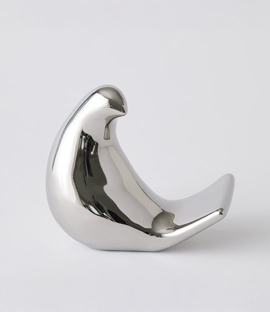 Silver bird-shaped object on a light gray background. Les Animaux–Moineau sculpture by Lemieux Et Cie