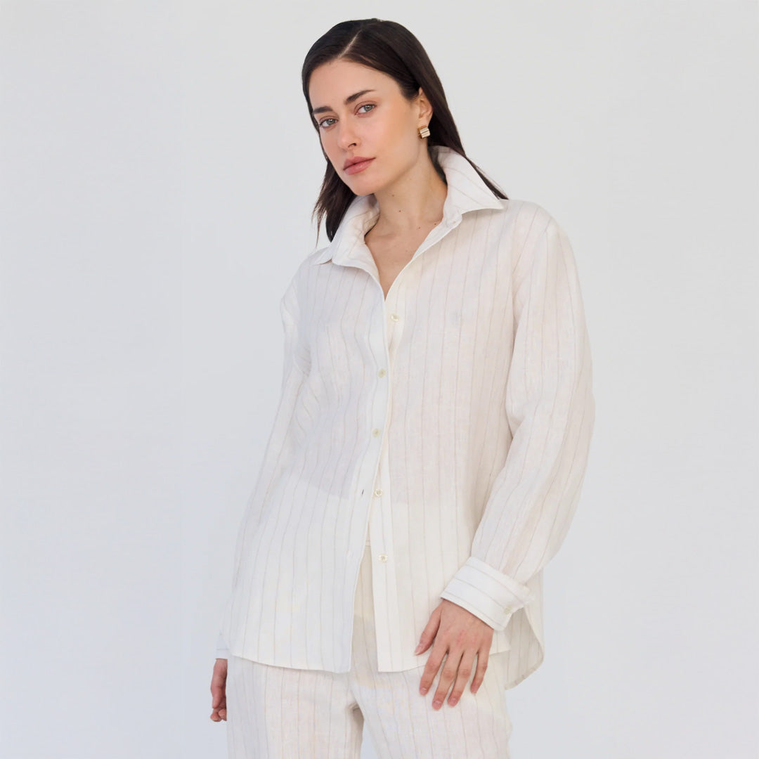 Woman wearing a white button-up shirt with a subtle pattern on a plain background