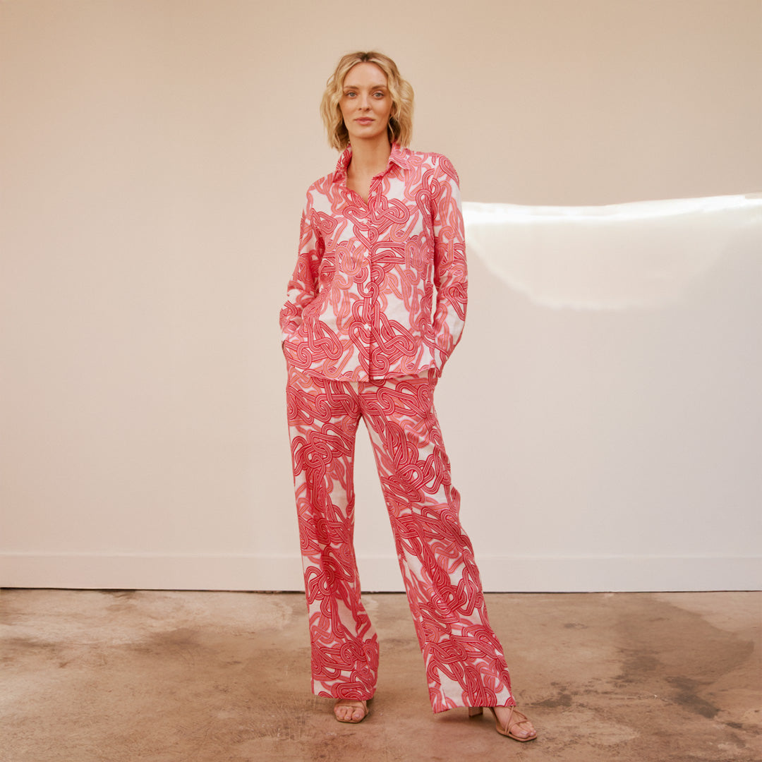 Woman wearing a pink and white patterned set against a neutral background