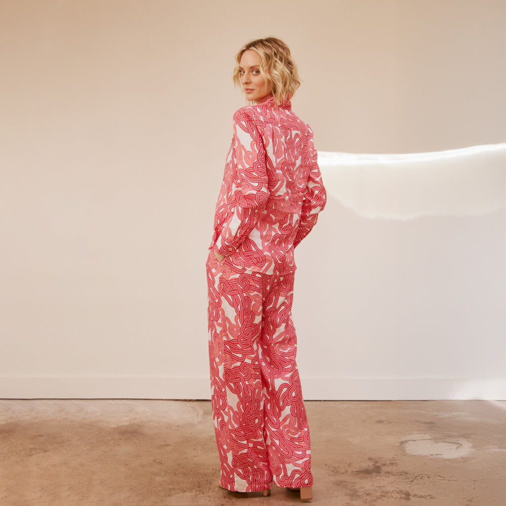 Person wearing a red and white patterned outfit standing against a neutral background