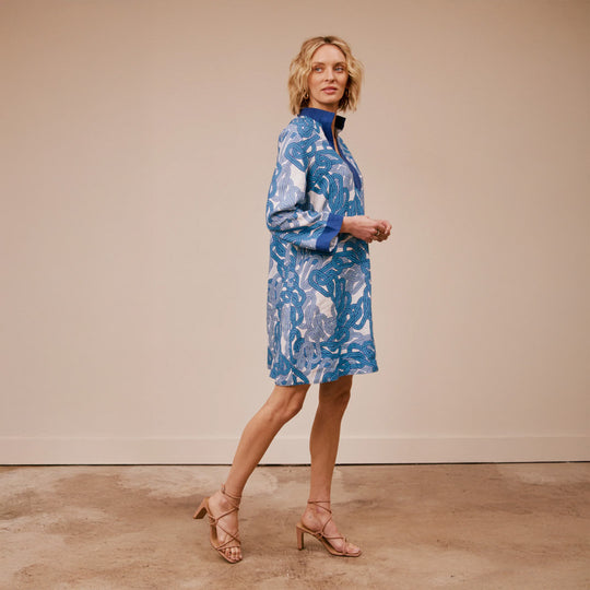 Woman wearing a blue patterned dress against a beige background