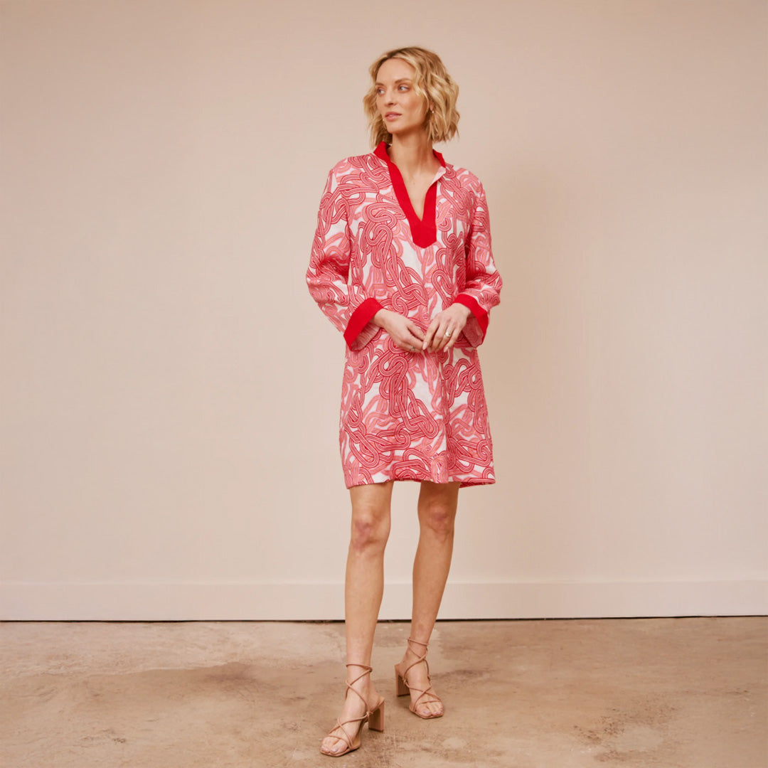 Woman wearing a red and white patterned dress against a beige background