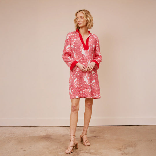 Woman wearing a red and white patterned dress against a beige background