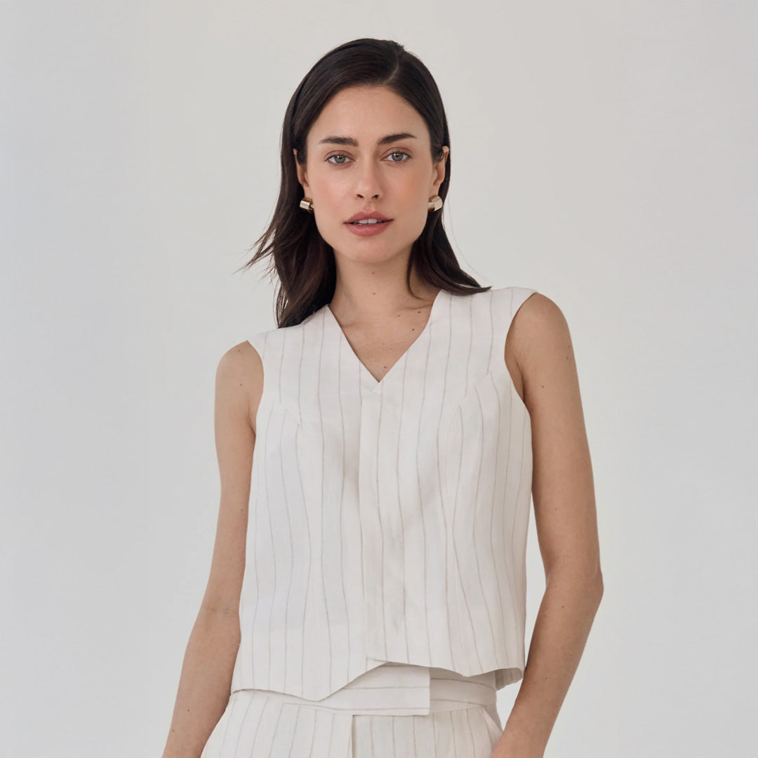 Woman wearing a white vest against a plain background
