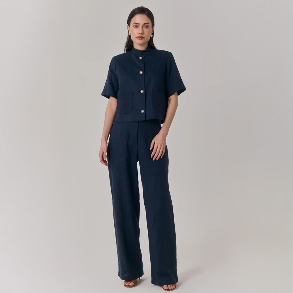 Woman wearing a navy blue outfit with a cropped jacket and wide-leg pants on a plain background