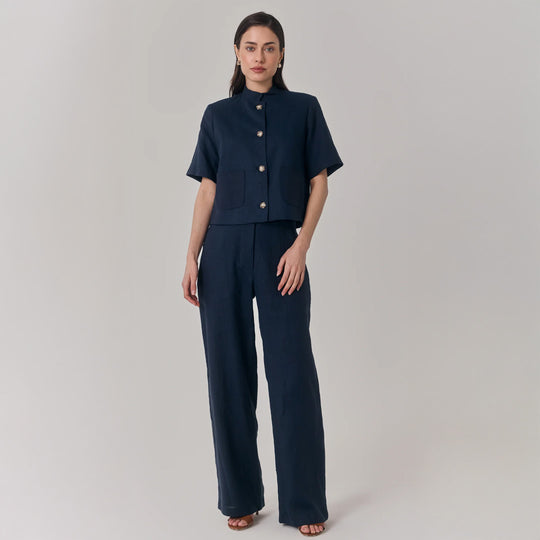 Woman wearing a navy blue outfit with a cropped jacket and wide-leg pants on a plain background