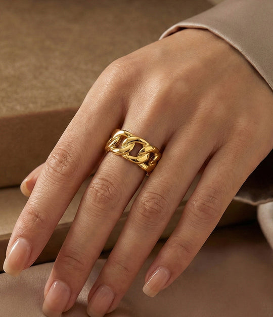 Gold chain ring on a hand against a neutral background