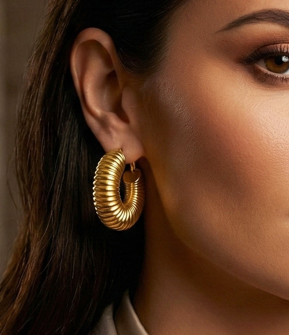 Close-up of a woman wearing a gold hoop earring with a neutral background