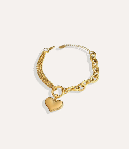 Gold chain bracelet with a heart charm on a white background