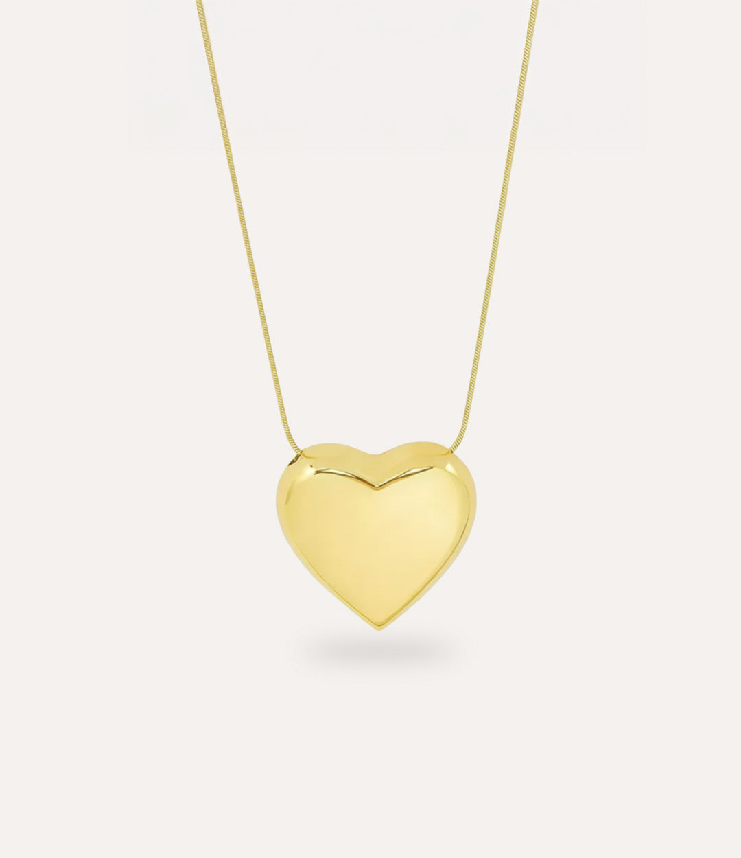 Gold heart-shaped pendant on a chain against a white background