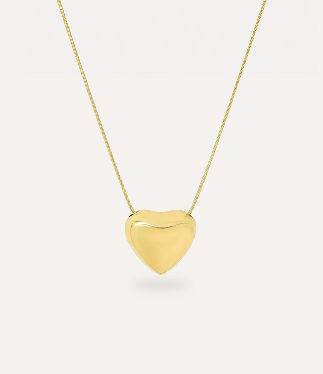 Gold heart-shaped pendant on a chain against a white background