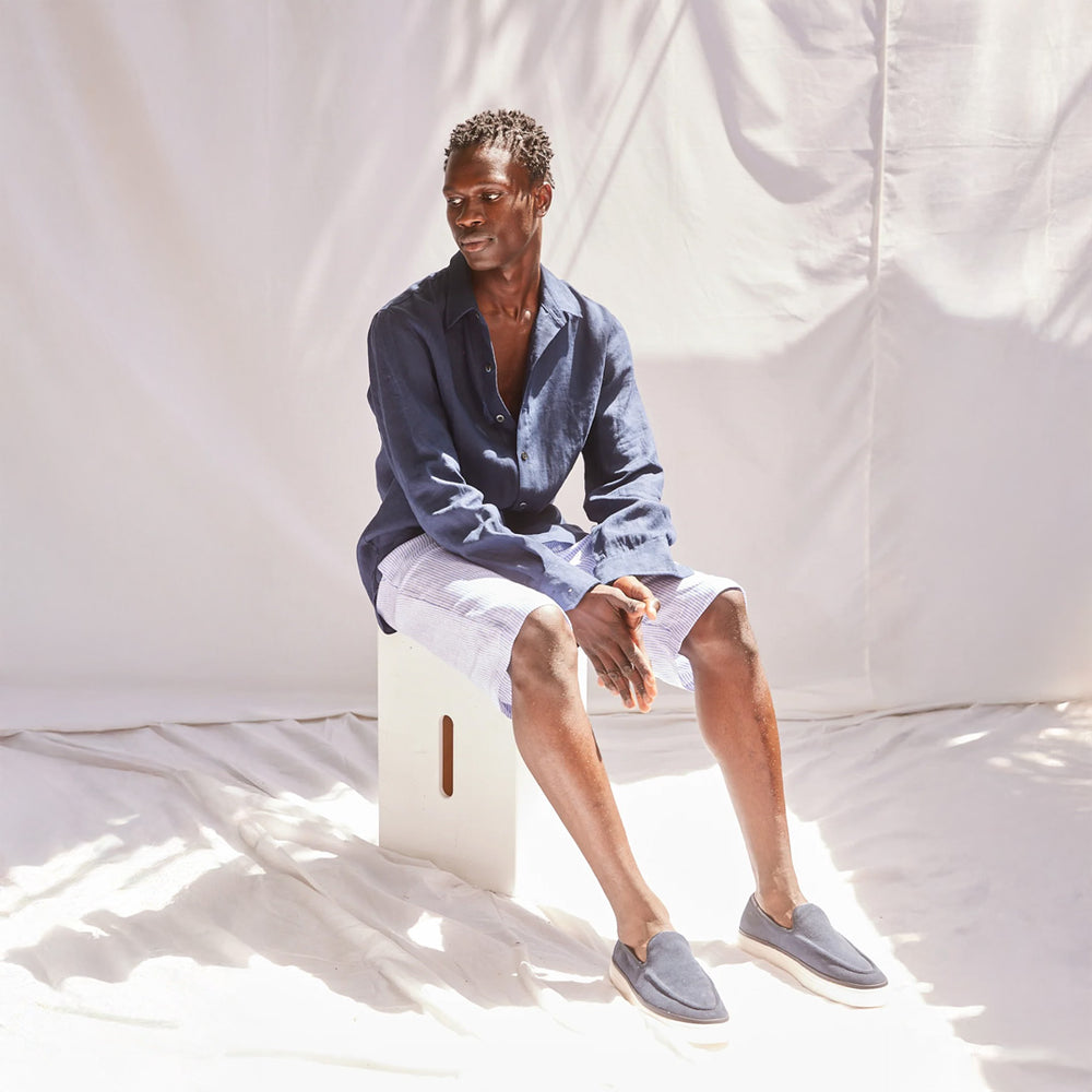 Person sitting on a stool against a plain white background