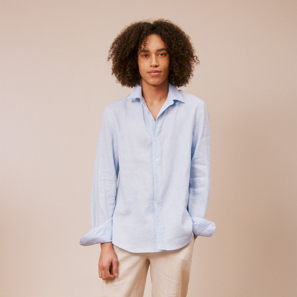 Person wearing a light blue shirt and beige pants against a beige background