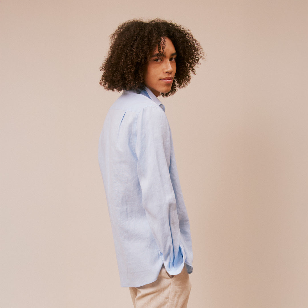 Person wearing a light blue shirt against a beige background