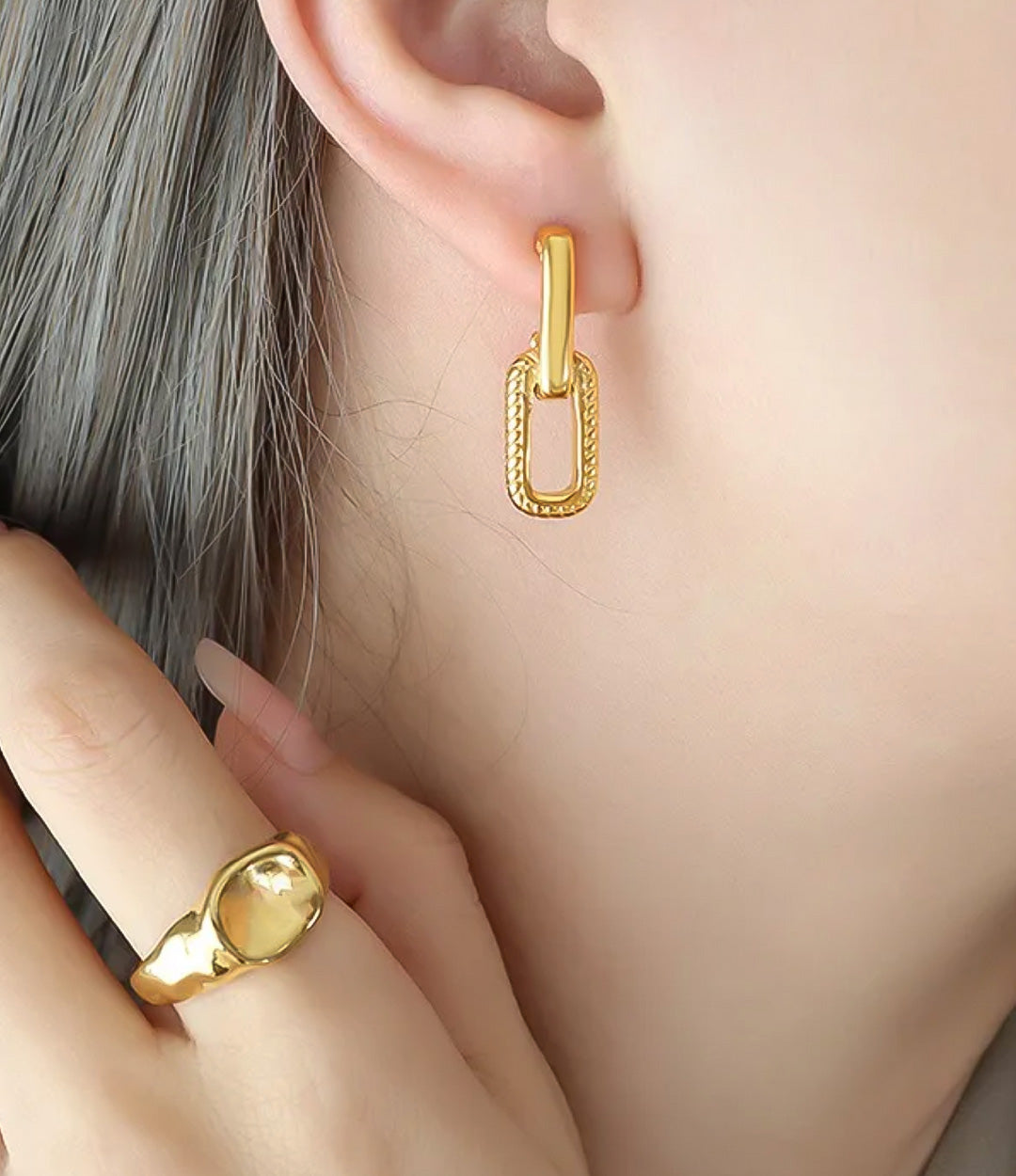 Close up of a model wearing the Mini Link Earrings showing the delicate hollow drop design and elegant fit against a neutral background.