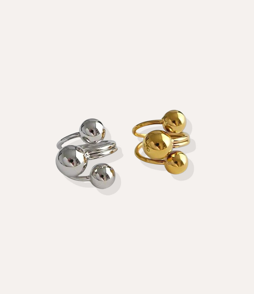 Gold and silver rings with spherical designs on a white background