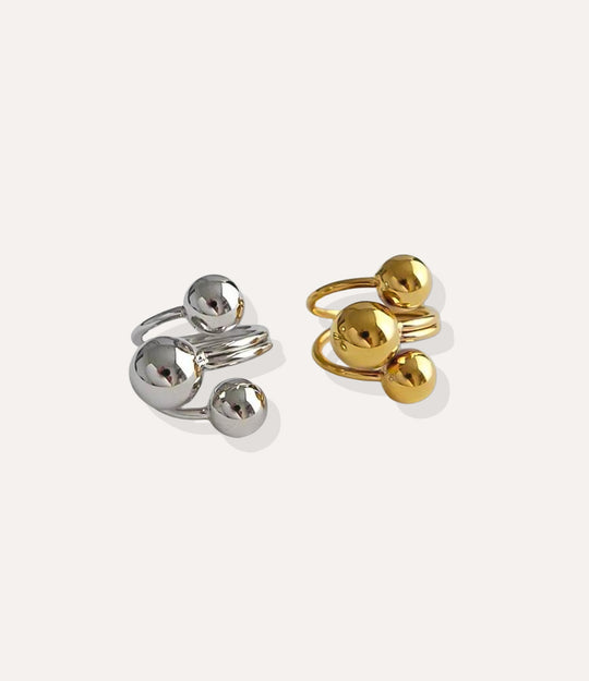 Gold and silver rings with spherical designs on a white background