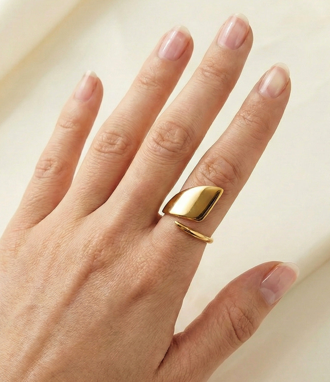 Model wearing Mod Ring in 18k gold plated finish, featuring a smooth, substantial statement design made of waterproof stainless steel, isolated on plain background.