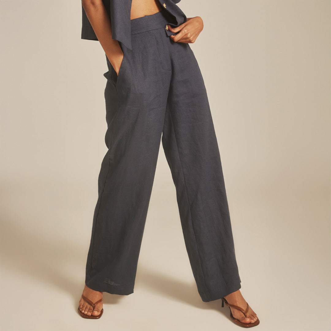 Person wearing dark gray wide-leg pants on a beige background