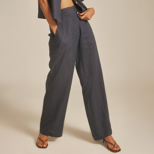 Person wearing dark gray wide-leg pants on a beige background