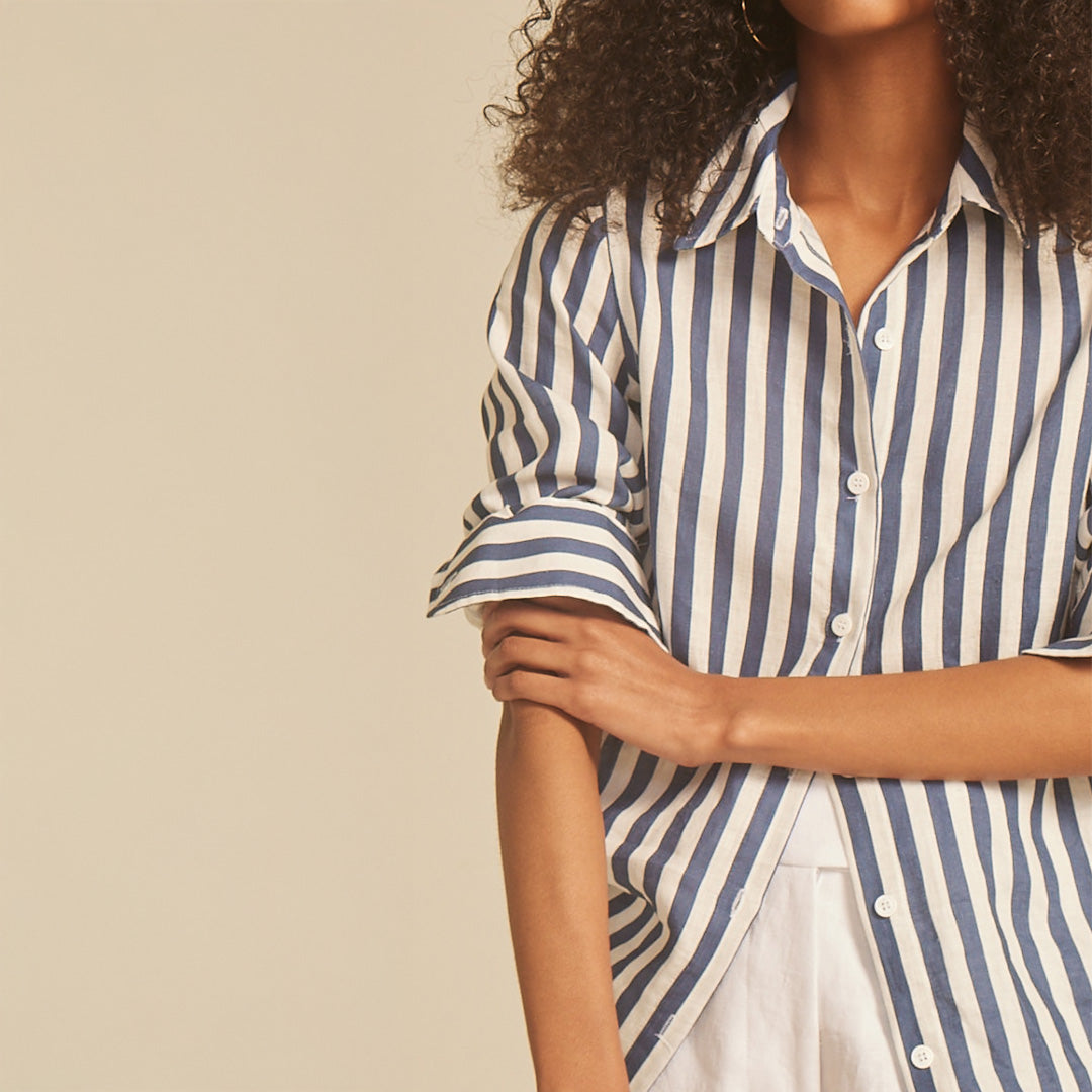 Person wearing a blue and white striped shirt against a beige background