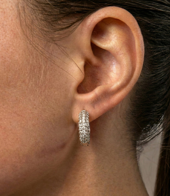 Close-up of a woman wearing silver hoop earrings with a blurred background