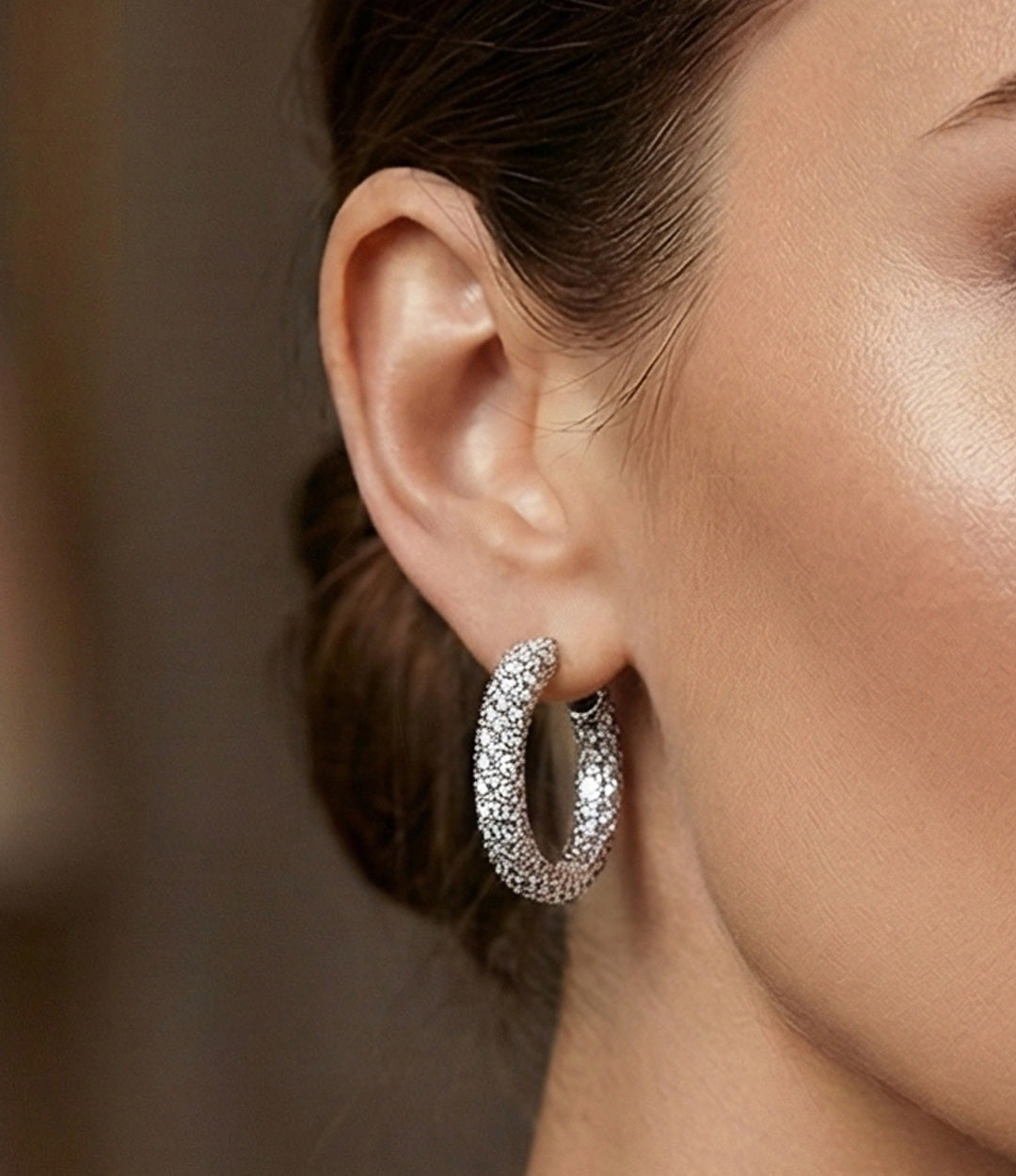 A woman wearing a silver hoop with diamonds