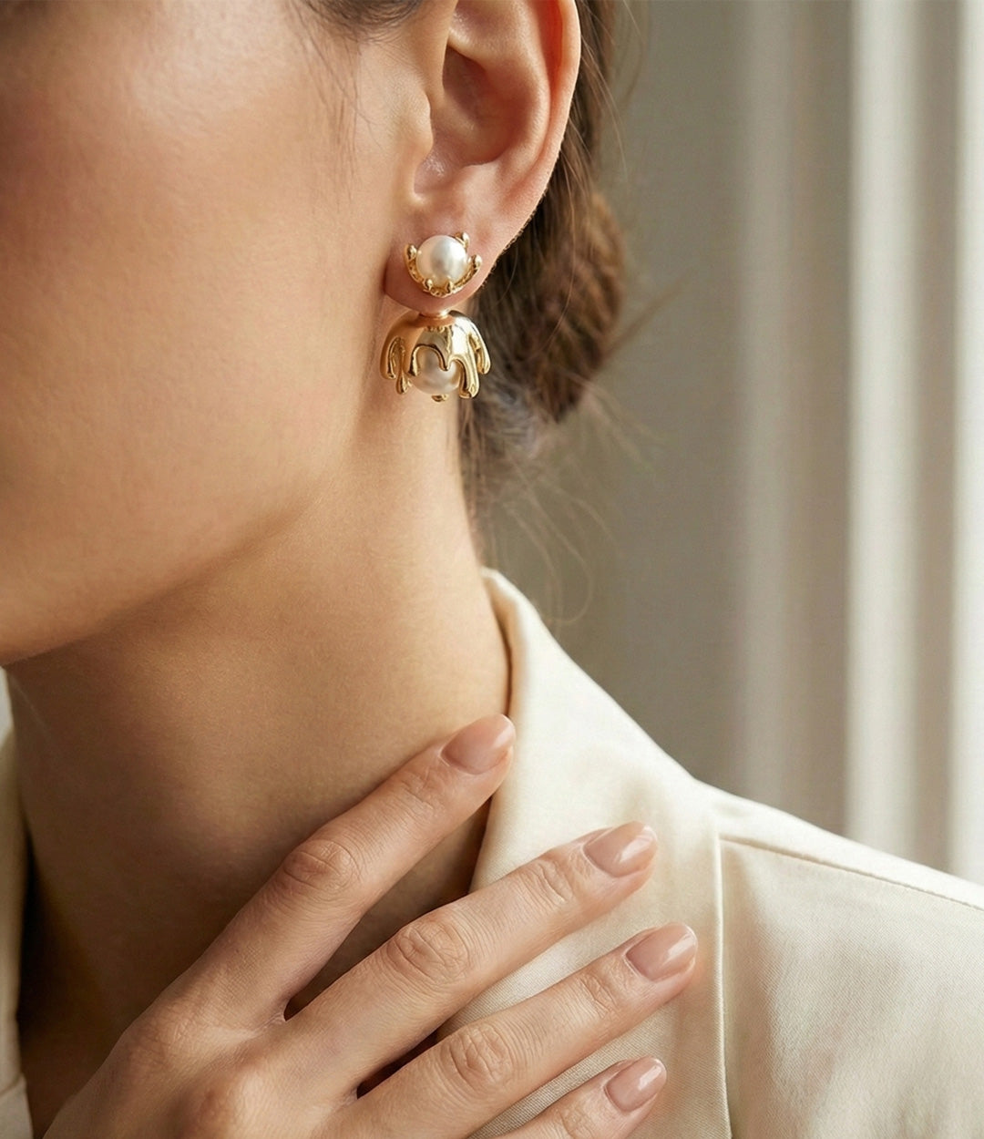 Close-up of a person wearing a gold earring with a pearl-like stone.