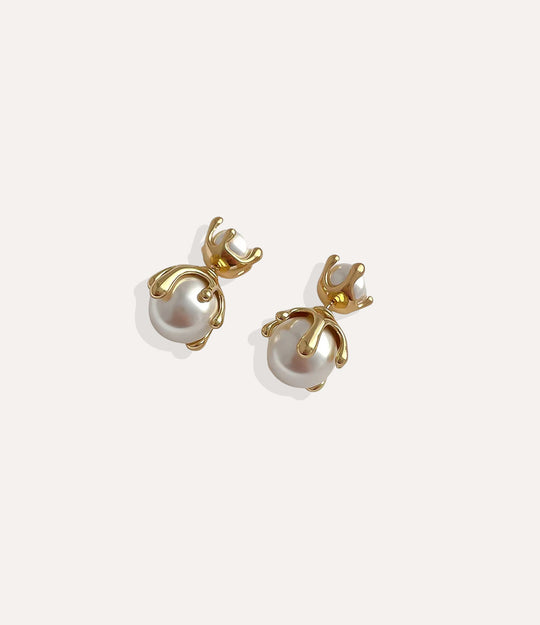 Close up of Pearl Drip Stud earrings in gold highlighting the sleek drip design and pearl accent.