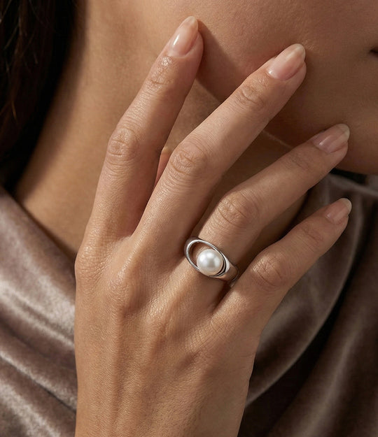 Woman's hand modeling the Pearl Drop Ring on the ring finger, showcasing the lustrous freshwater pearl and the sleek, elegant band design.