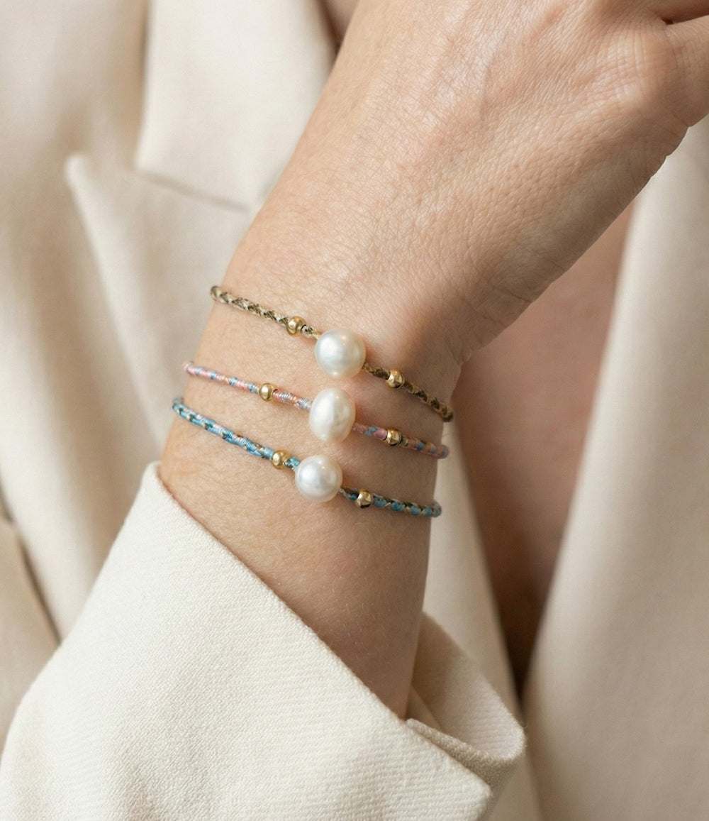 Three pearl bracelets on a wrist with a neutral background