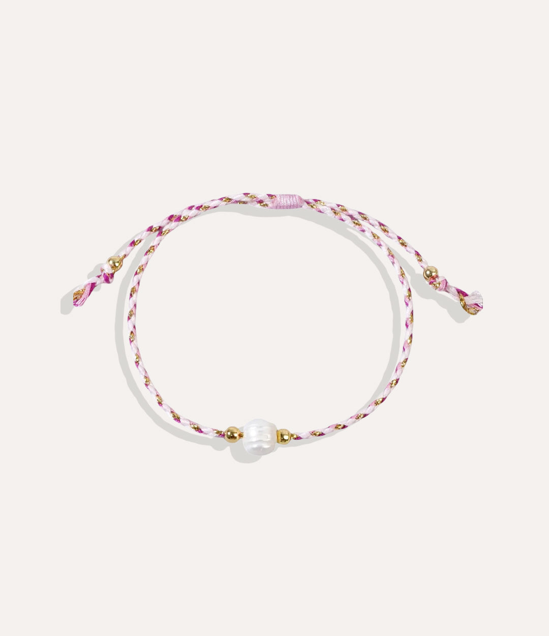 Pearl on a pink string bracelet displayed on a neutral background showcasing its vibrant cord and glossy pearl.